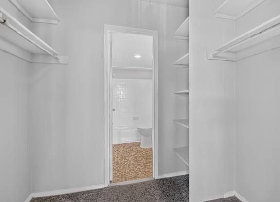 A white room with a doorway leading to a bathroom.