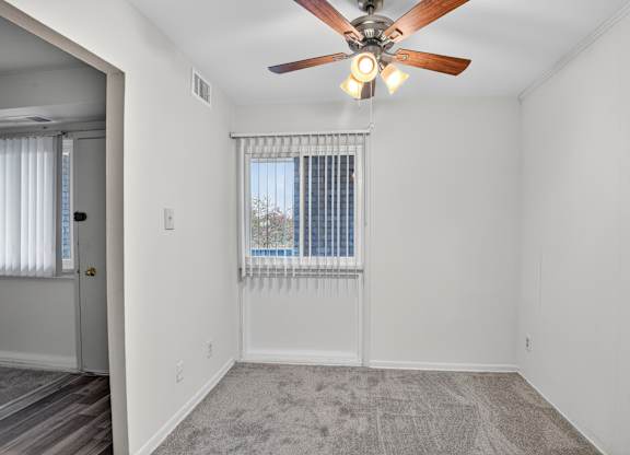 A  dining room with a ceiling fan and a window with blinds.