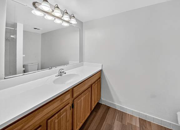A bathroom with a white countertop and wooden cabinets.