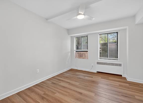A room with a window and a fan on the ceiling.
