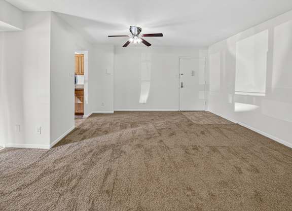 A spacious room with a ceiling fan and carpeted floor.