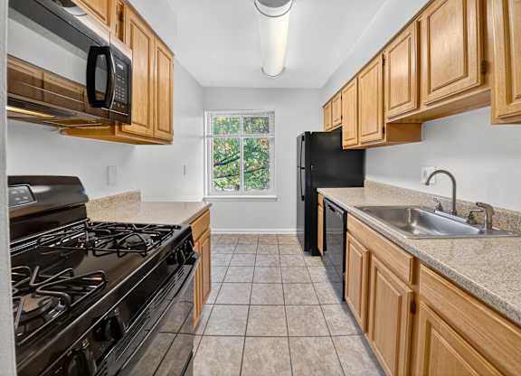 A kitchen with a black stove top oven and black microwave.