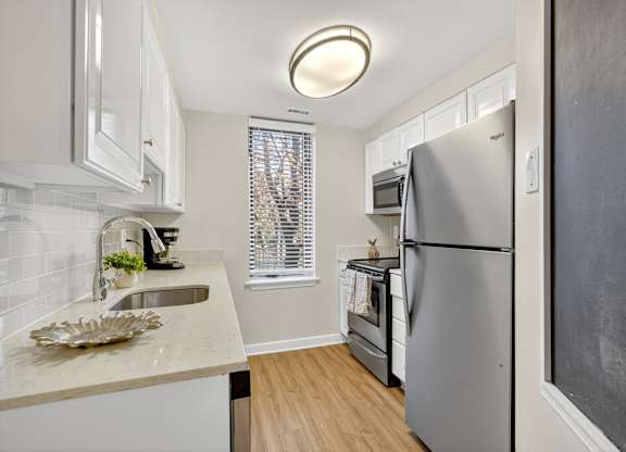 A kitchen with a refrigerator, sink, and window.