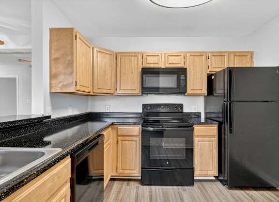 A kitchen with black appliances and wooden cabinets.