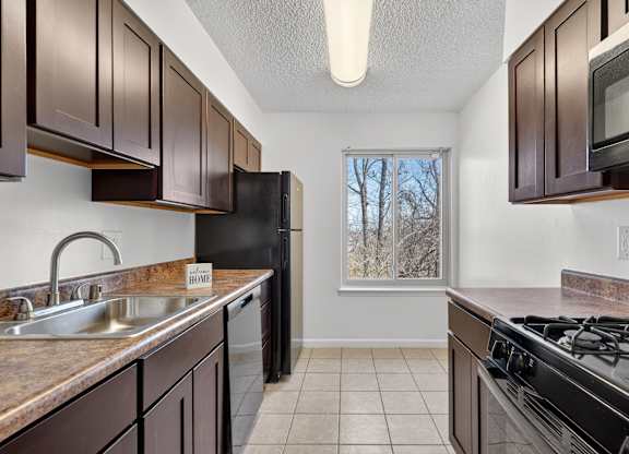 A kitchen with brown cabinets and black appliances.