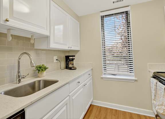 A kitchen with white cabinets and a stainless steel sink.