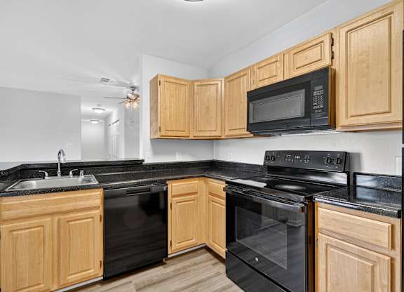 A kitchen with black appliances and wooden cabinets.