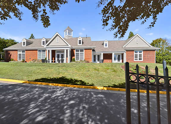 A red brick building with a black fence in front.