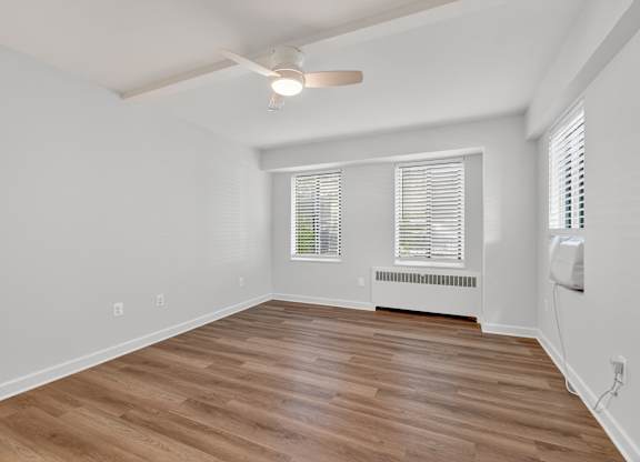 A room with a ceiling fan and wooden flooring.