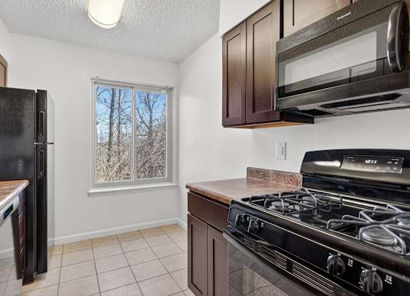 A kitchen with black appliances and brown cabinets.