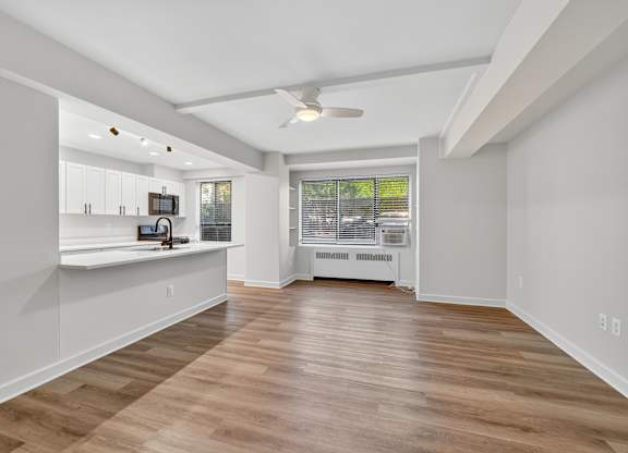 A spacious room with wooden flooring and a ceiling fan.