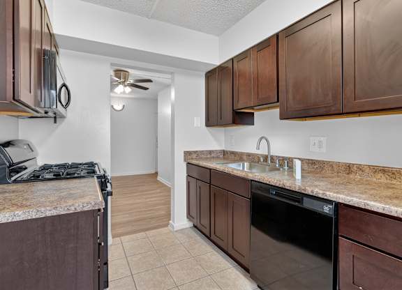 A kitchen with brown cabinets and a black dishwasher.