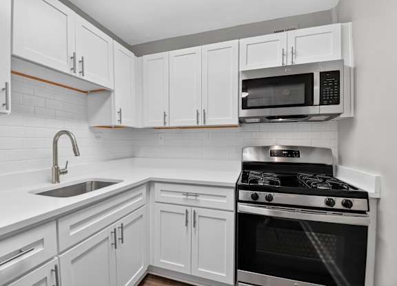 A kitchen with white cabinets and a black stove.