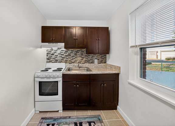 A kitchen with white appliances and brown cabinets.
