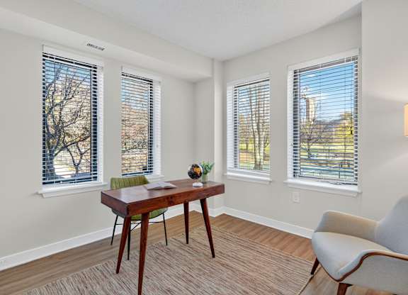 A room with a table, chairs and windows.