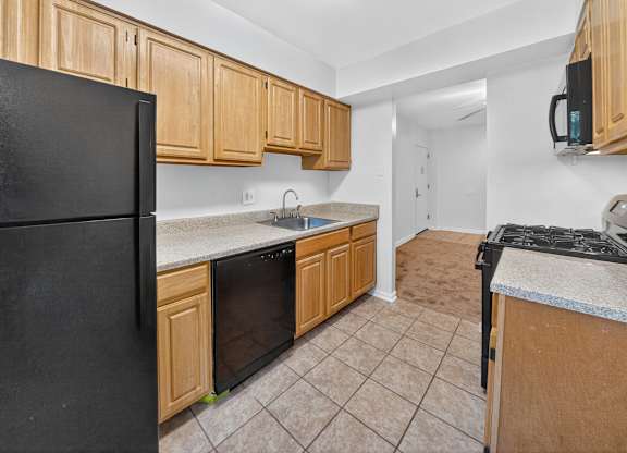 A kitchen with black appliances and wooden cabinets.