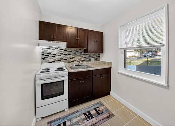 A kitchen with white appliances and brown cabinets.