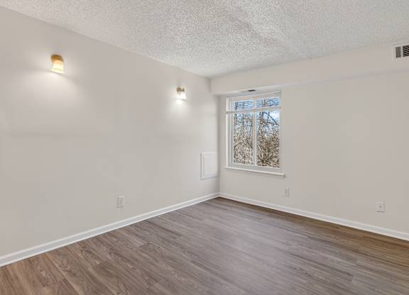 A room with light wood flooring and white walls.