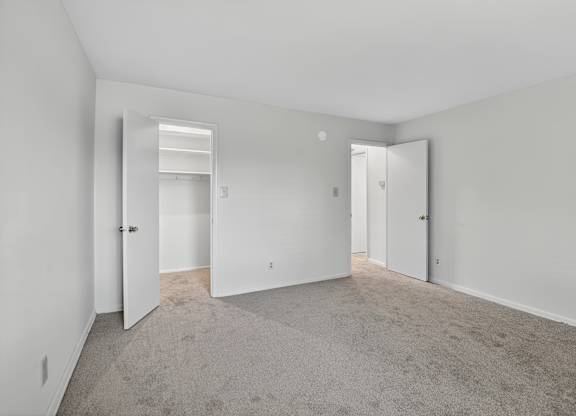 A large, empty room with carpeted flooring and white walls.