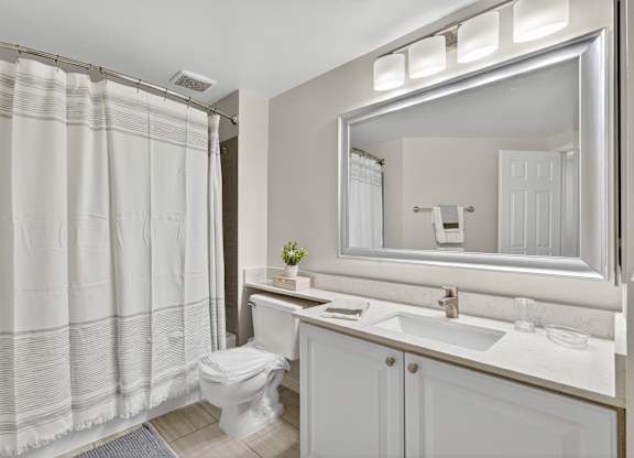 A white bathroom with a toilet, sink, and shower curtain.