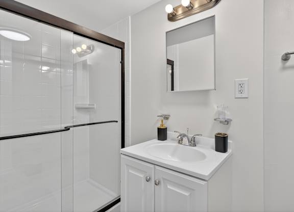 A white bathroom with a sink and mirror.