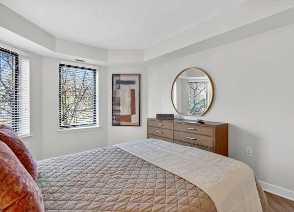 A bedroom with a large bed, a dresser, and a mirror.