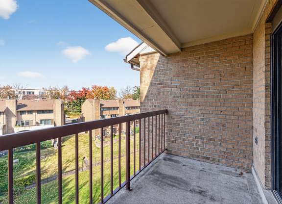 A balcony with a brick wall and a metal railing.