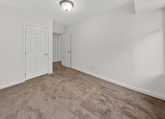 A room with carpeted floor and two doors.