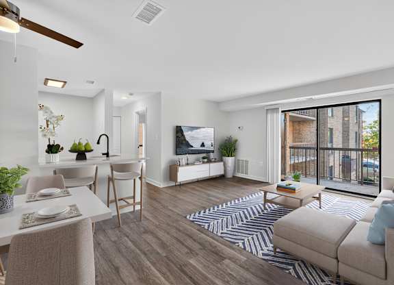 A living room with a couch, a dining table, and a television.