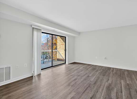 A room with a sliding glass door leading to a balcony.