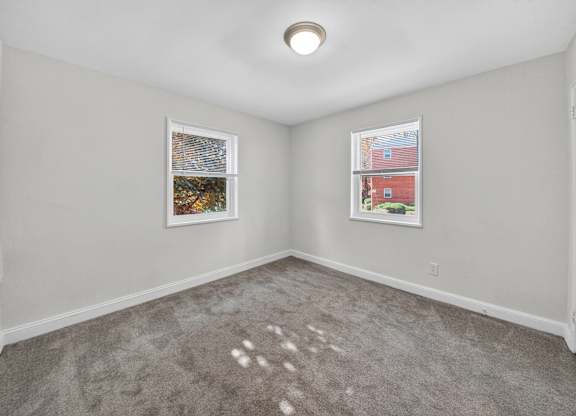 A room with a grey carpet and two pictures on the wall.