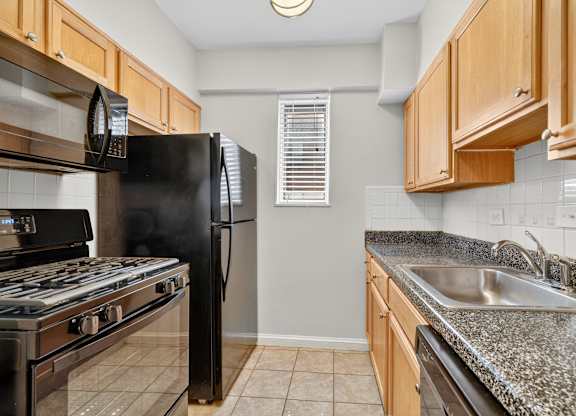 A kitchen with black appliances and wooden cabinets.