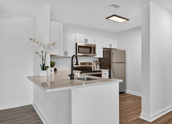 A kitchen with white cabinets and a stainless steel refrigerator.