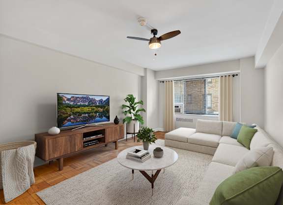 A living room with a flat screen TV, a white couch, and a coffee table.