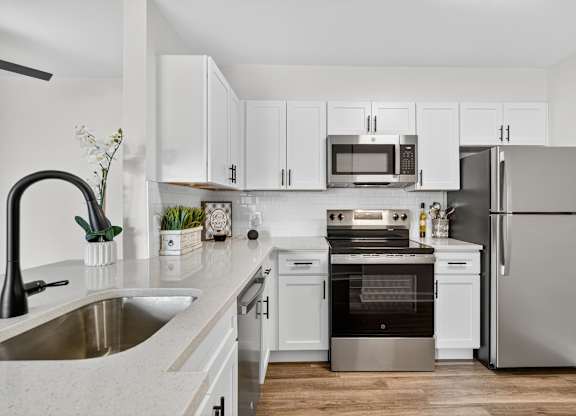 A modern kitchen with white cabinets and stainless steel appliances.