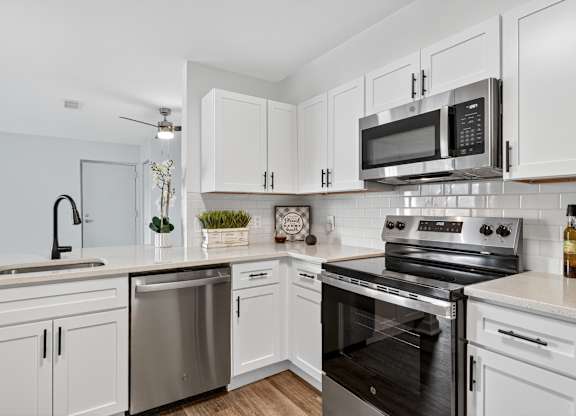 A modern kitchen with white cabinets and stainless steel appliances.