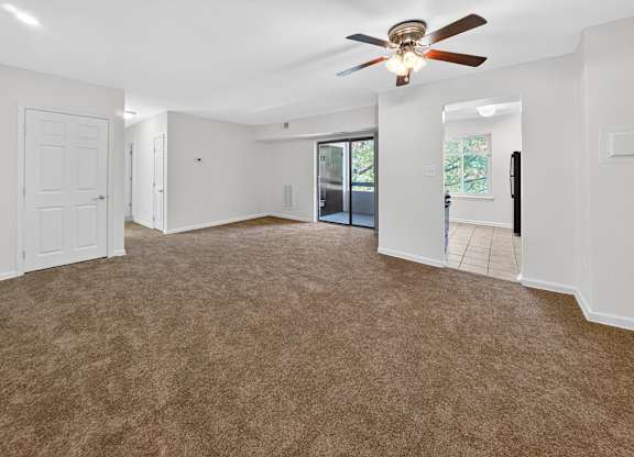 A room with a ceiling fan and carpeted floor.