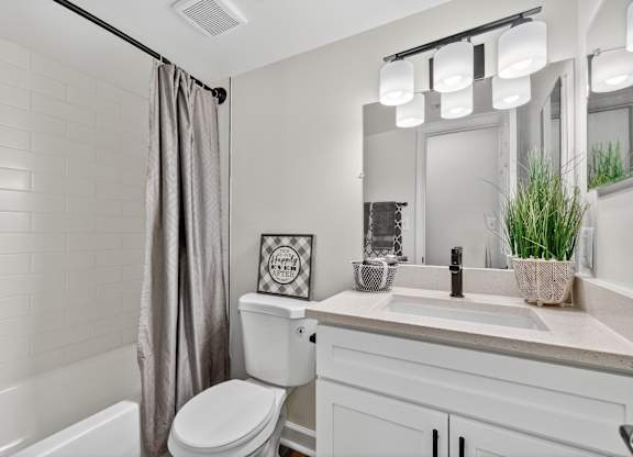 A white bathroom with a toilet, sink, and a mirror.