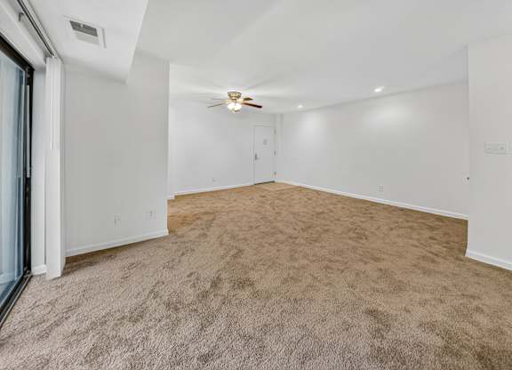 A room with a carpeted floor and a ceiling fan.
