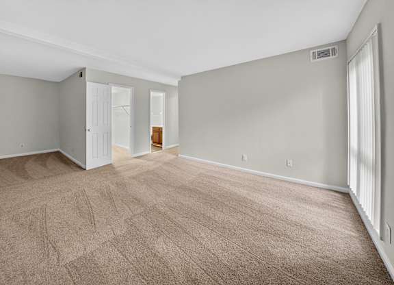 A room with a carpeted floor and a doorway leading to another room.