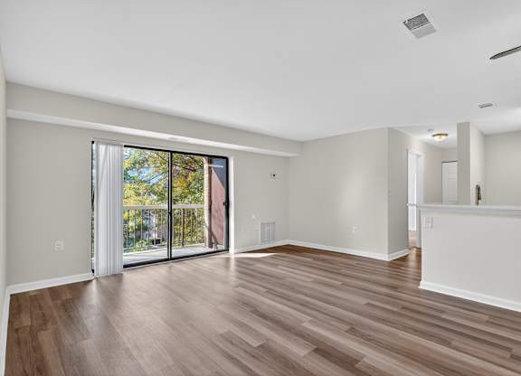 A room with wooden flooring and sliding glass doors.