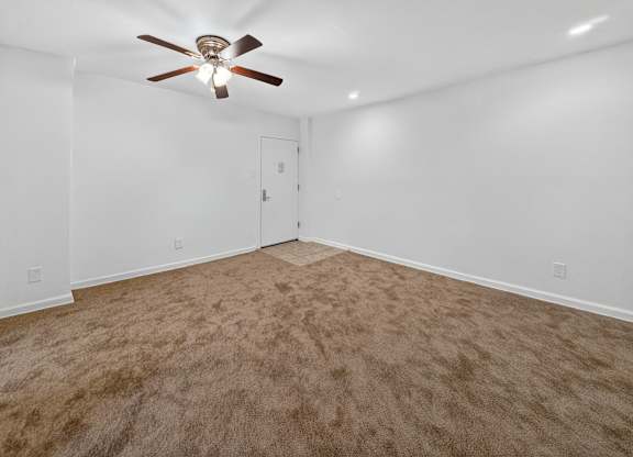 A room with a ceiling fan and carpeted floor.