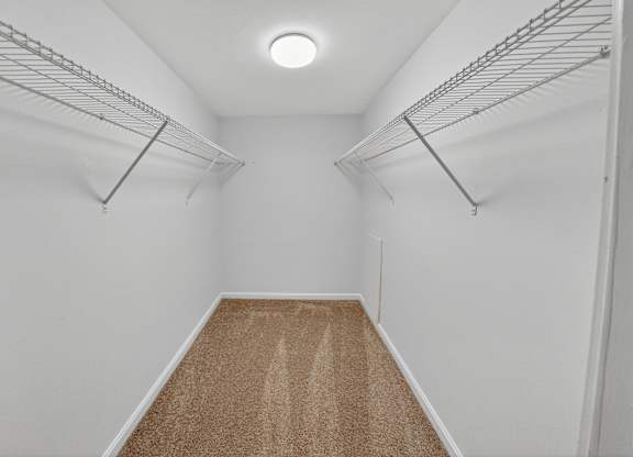 Empty walk-in closet with carpeted floor and metal racks.