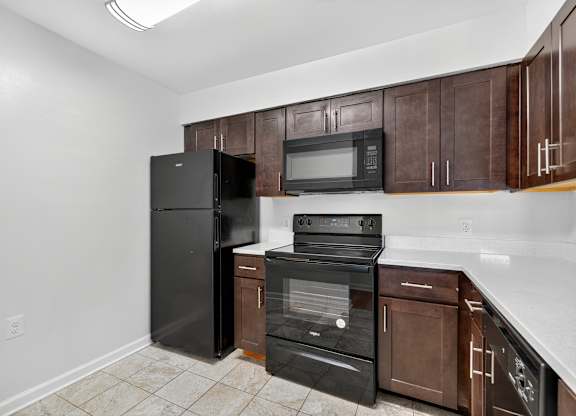 A kitchen with black appliances and brown cabinets.