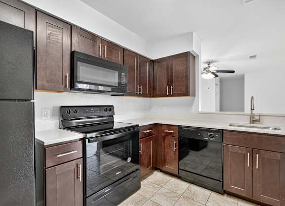 A kitchen with brown cabinets and black appliances.