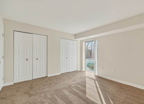 A room with white doors and carpeted floor.