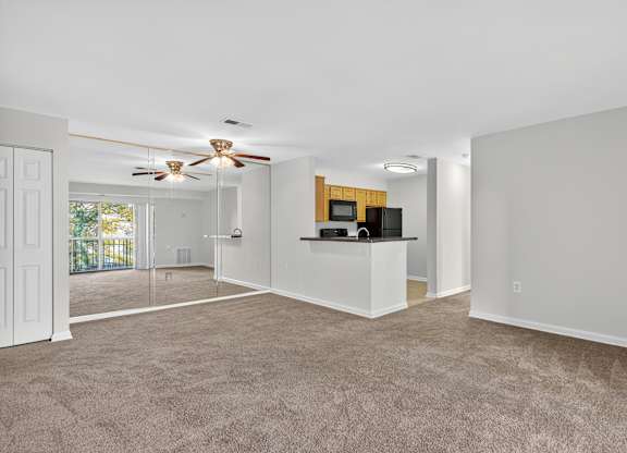 A spacious living room with a ceiling fan and a bar area.
