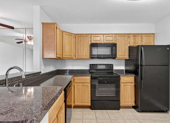 A kitchen with black appliances and wooden cabinets.