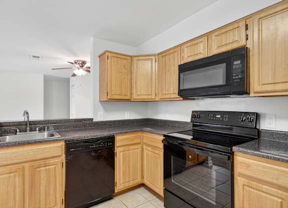 A kitchen with black appliances and wooden cabinets.