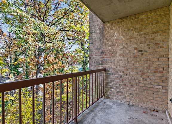 A balcony with a brick wall and a metal railing.
